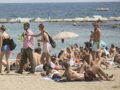 Una agent de la Guàrdia Urbana de paisà para a un venedor de mojitos aquest dimecres en la Barceloneta.
