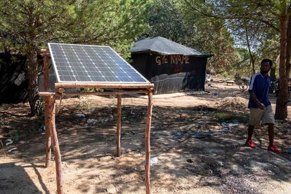 Un inmigrante pasa junto a una placa solar, esta semana, en un asentamiento de Lucena del Puerto (Huelva).