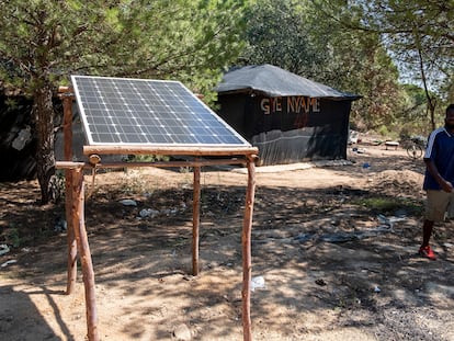 Un inmigrante pasa junto a una placa solar, esta semana, en un asentamiento de Lucena del Puerto (Huelva).