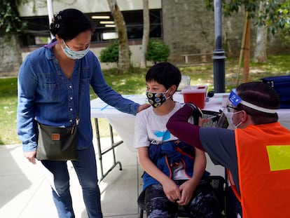 Colin Sweeney, de 12 años, recibe una inyección de la vacuna Pfizer mientras su madre Nicole le da una palmada en el hombro en la Primera Iglesia Bautista de Pasadena en Pasadena, California.