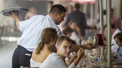 Un camarero atiende una terraza en Sevilla. 