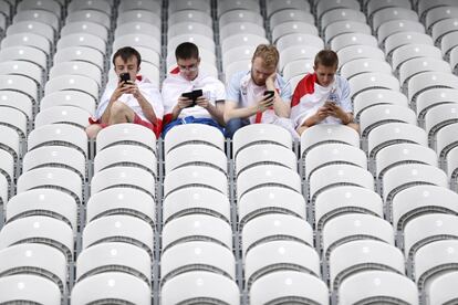 Cuatro hinchas ingleses pendientes de sus teléfonos antes del comienzo del partido contra Gales. 