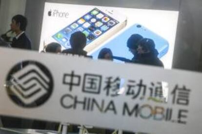 Varias personas preguntan por el nuevo iPhone 5s en una oficina de China Mobile durante el lanzamiento este viernes del nuevo teléfono en Pekín (China).