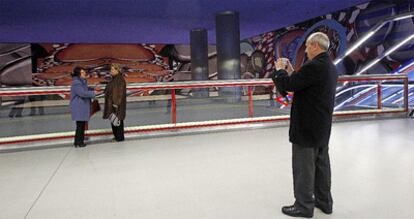 Unos viajeros se fotografan en la estacin de Alsacia, con el mural de Gordillo al fondo.