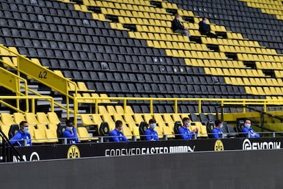 En esta imagen de los jugadores suplentes del Schalke 04 en el banquillo del estadio del Borussia Dortmund se observa cómo entre cada uno debe haber una separación mínima.