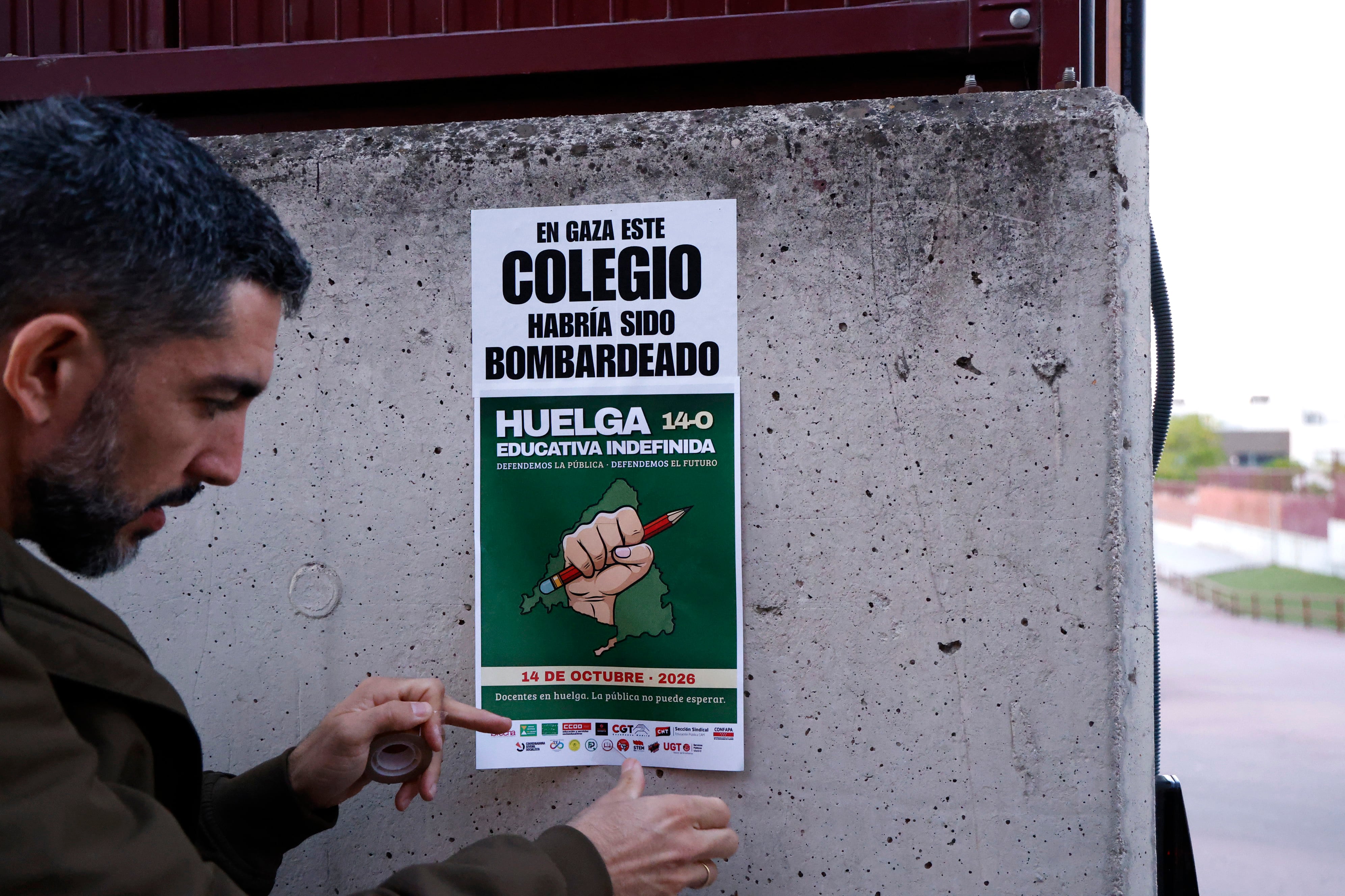Un hombre coloca un cartel sobre la huelga educativa en un instituto de Vallecas, este miércoles.
