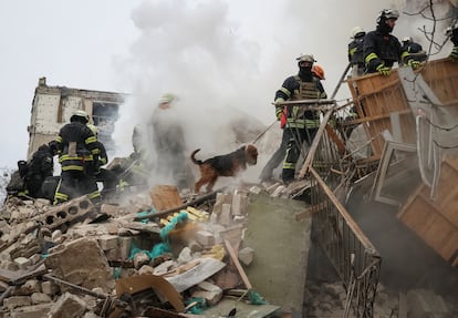 Rescuers with a dog work at a site of a residential building heavily damaged during a Russian missile attack.