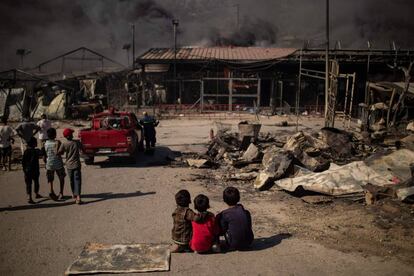 Un grupo niños migrantes observa el incendio del campamento de Moria.