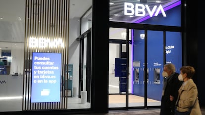 Una pareja pasa frente a una oficina del BBVA.