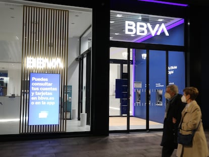 Una pareja pasa frente a una oficina del BBVA, este lunes en Bilbao, día en que se ha conocido que las entidades BBVA y Banco Sabadell mantienen contactos preliminares para una posible fusión.