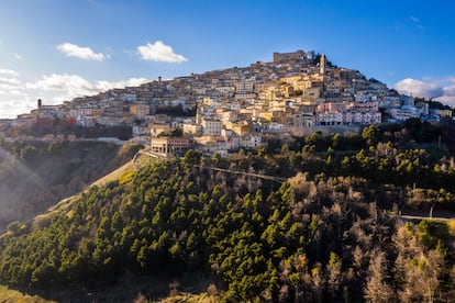 Sant’Agata di Puglia, conocido como el “balcón de Apulia”, mantiene intacto el misterio de una aldea medieval de montaña con un laberinto de ‘trasonne’ (callejones) que se extienden hasta el castillo situado en lo alto. Las vistas desde la plaza principal dejan sin aliento. Y por la noche, de lejos, el pueblo parece un árbol de Navidad iluminado.
Sant’Agata está en el interior, en el corazón de Apulia, y es uno de esos lugares fascinan­tes, donde un simple paseo es suficiente para despertar nuestra curiosidad. Desde sus 800 metros de altitud se goza de unas vistas amplias y emocionantes del valle del río Carapelle y hasta el bajo Tavoliere, desde el promontorio del Gargano hasta el golfo de Manfredonia. El lugar es espectacular, sobre todo hacia el atardecer, cuando se van encen­diendo lentamente las luces de las casas y de las calles, que convergen en la plaza y, más a lo alto, en el castillo. En la Piazza XX Settembre hay una hermosa te­rraza panorámica adornada con macetas, que es como un balcón con un paisaje ilimitado de campos y bosques coronado por el perfil inconfundible del monte Vulture. Resulta agradable (aunque un poco agotador) recorrer el pueblo medie­val, entre pequeñas casas de tejados unifor­mes de terracota, descubriendo los símbolos heráldicos y los hermosos portales de piedra tallada que ennoblecen las fachadas con ca­riátides, escudos, máscaras y motivos vege­tales.
Hay otros encantos a descubrir en la naturaleza que rodea Sant’Agata: en el bosque de Serbaroli, a lo largo de la carretera de Ac­cadia, se alza el megalito llamado Pietra di Sandu Linze (San Lorenzo) y su pozo sagrado.