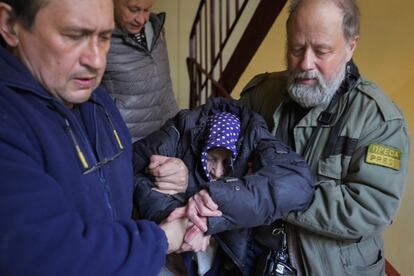 Voluntarios ayudan a una anciana a bajar las escaleras de un refugio antiaéreo en Járkov. Rusia proseguirá su asedio sobre ciudades ucranianas, que son víctimas de bombardeos aéreos y de artillería, pero previsiblemente optará por no entrar en combates urbanos con su infantería, según el último análisis del Ministerio británico de Defensa.