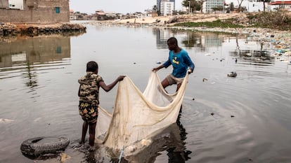 Dos niños usan una red para pescar en un lago cerca de Luanda (Angola), en agosto de 2022.