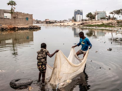 Dos niños usan una red para pescar en un lago cerca de Luanda (Angola), en agosto de 2022.