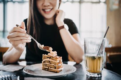 Una mujer disfruta de una tarta con té helado en una cafetería.