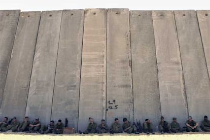 Soldados israelíes descansan a la sombra del muro que separa a Israel de la franja de Gaza.