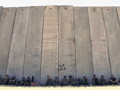 Soldados israelíes descansan a la sombra del muro que separa a Israel de la franja de Gaza.