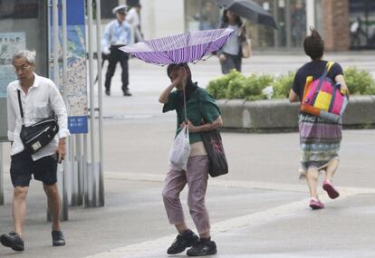 Una mujer trata de sostener su paraguas frente a los fuertes vientos en Yokohama (Japón).
