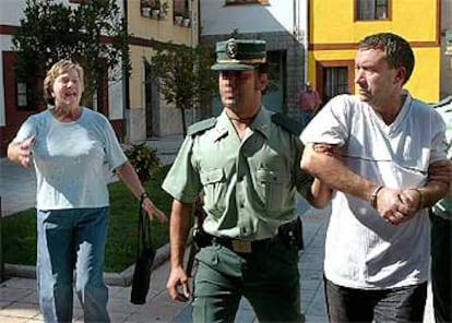 Una mujer increpa a A. F. L. que es conducido por agentes de la Guardia Civil al Juzgado de Grado.