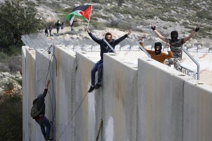 Un grupo de manifestantes palestinos escala el muro de separación con Israel durante una manifestación que conmemora el 12º aniversario de su campaña contra la barrera, en la aldea de Bilin, cerca de Ramala (Cisjordania).
