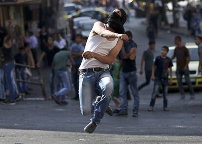 Un palestino arroja una piedra contra las fuerzas de seguridad israelíes en Hebrón.