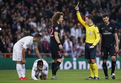 El arbitro Mark Clattenburg saca tarjeta amarilla al jugador del PSG David Luiz después de golpear a Isco