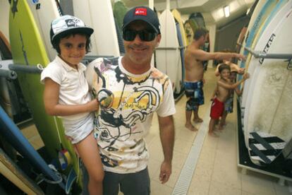 Aitor Francesena, con su hija en brazos en su escuela de surf.