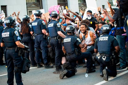 Un hombre grita de emoción al ver a un policía arrodillado mientras cientos de personas protestan por la muerte de George Floyd en Washington (EE UU).