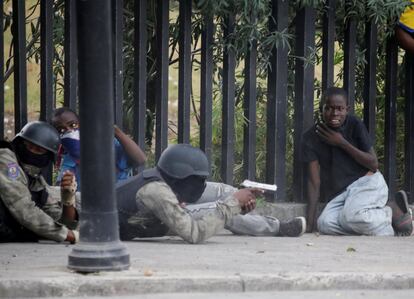 Un joven observa a un miembro de la Policía Nacional de Haití que apunta con un arma, en Champ de Mars.