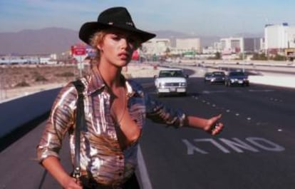 Nomi Malone, personaje de Elizabeth Berkley, espera a que algún alma caritativa la lleve en su coche.