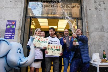 El dueño y los empleados del establecimiento de lotería donde ha tocado el segundo premio del sorteo de El Niño celebran en la calle Arenal en Madrid. 