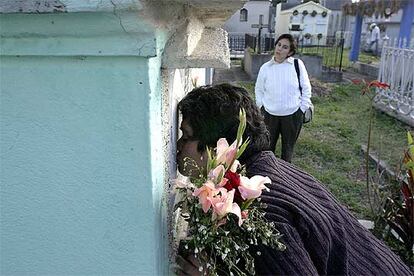 Rosa Franco besa la tumba de su hija María Isabel, acompañada de María Elena Peralta, hermana de otra víctima.