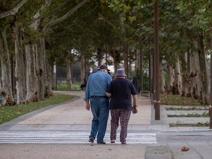 Una pareja de ancianos camina por la calle agarrada del brazo.