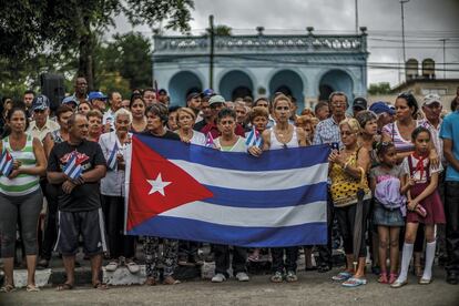 Un grupo de cubanos se concentra alrededor de una bandera al paso del féretro de Fidel Castro.