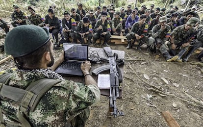 TO GO WITH AFP STORY by Hector Velasco
Tomas (L), a member of the Revolutionary Armed Forces of Colombia (FARC), talks about the peace process between the Colombian government and their force, to guerrillas during a "class" at a camp in the Colombian mountains on February 18, 2016. They still wear green combat fatigues and carry rifles and machetes, but now FARC rebel troops are sitting down in the jungle to receive "classes" on how life will be when they lay down their arms, if their leaders sign a peace deal in March as hoped.  AFP PHOTO / LUIS ACOSTA