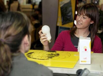 Una joven obtiene una bombilla de bajo consumo en una oficina de Correos de Zaragoza