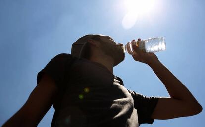 Un hombre joven bebe una botella de agua mineral en la Puerta del Sol.