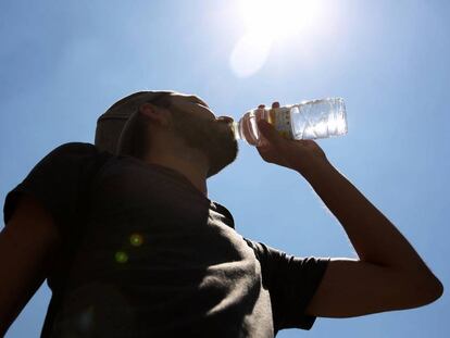 Un hombre joven bebe una botella de agua mineral en la Puerta del Sol.
