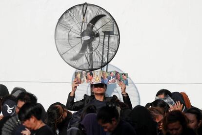 Una mujer se protege del sol mientras espera la comitiva con los restos del rey del Bhumibol Adulyadej.