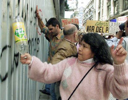 Un grupo de ahorradores protesta frente a una sucursal de Citibank protegida con una chapa de acero.