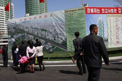 Ciudadanos norcoreanos observan un cartel anunciador de un nuevo proyecto de desarrollo residencial en Pionyang (Corea del Norte).