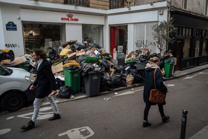 La gente camina por la calzada de una calle en París, ya que la acumulación de basura no permite caminar por las aceras, este lunes.
