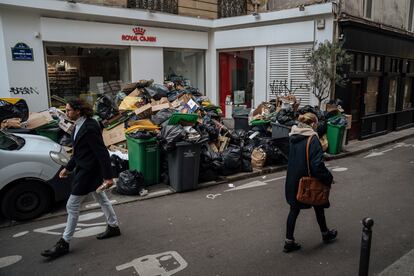 La gente camina por la calzada de una calle en París, ya que la acumulación de basura no permite caminar por las aceras, este lunes.