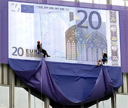 Dos empleados desvelan una reproducción gigante de un billete de 20 euros en la sede del BCE en Francfort.