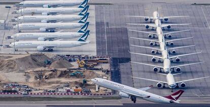 Un avión Cathay Dragon despega del aeropuerto de Hong Kong mientras varios aparatos de Cathay Pacific permanecen aparcados. 