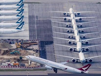 Un avión Cathay Dragon despega del aeropuerto de Hong Kong mientras varios aparatos de Cathay Pacific permanecen aparcados. 