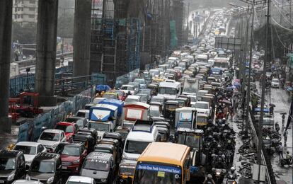 Una calle abarrotada de coches y peatones, que utilizan paraguas para protegerse de las lluvias del monzón, en Bombay (India).