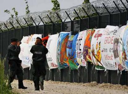 Policías toman fotos de las pancartas colocadas por grupos antiglobalización en la valla metálica de seguridad donde se celebrará la cumbre.