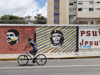 Un hombre pasa en su bicicleta frente a un mural con la imagen del presidente de Venezuela, Nicolás Maduro, y de Ernesto "Che" Guevara, en Caracas.