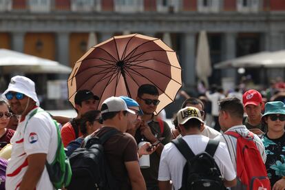 Un grupo de turistas se protegen del sol con gorros y paraguas, este miércoles en Madrid.